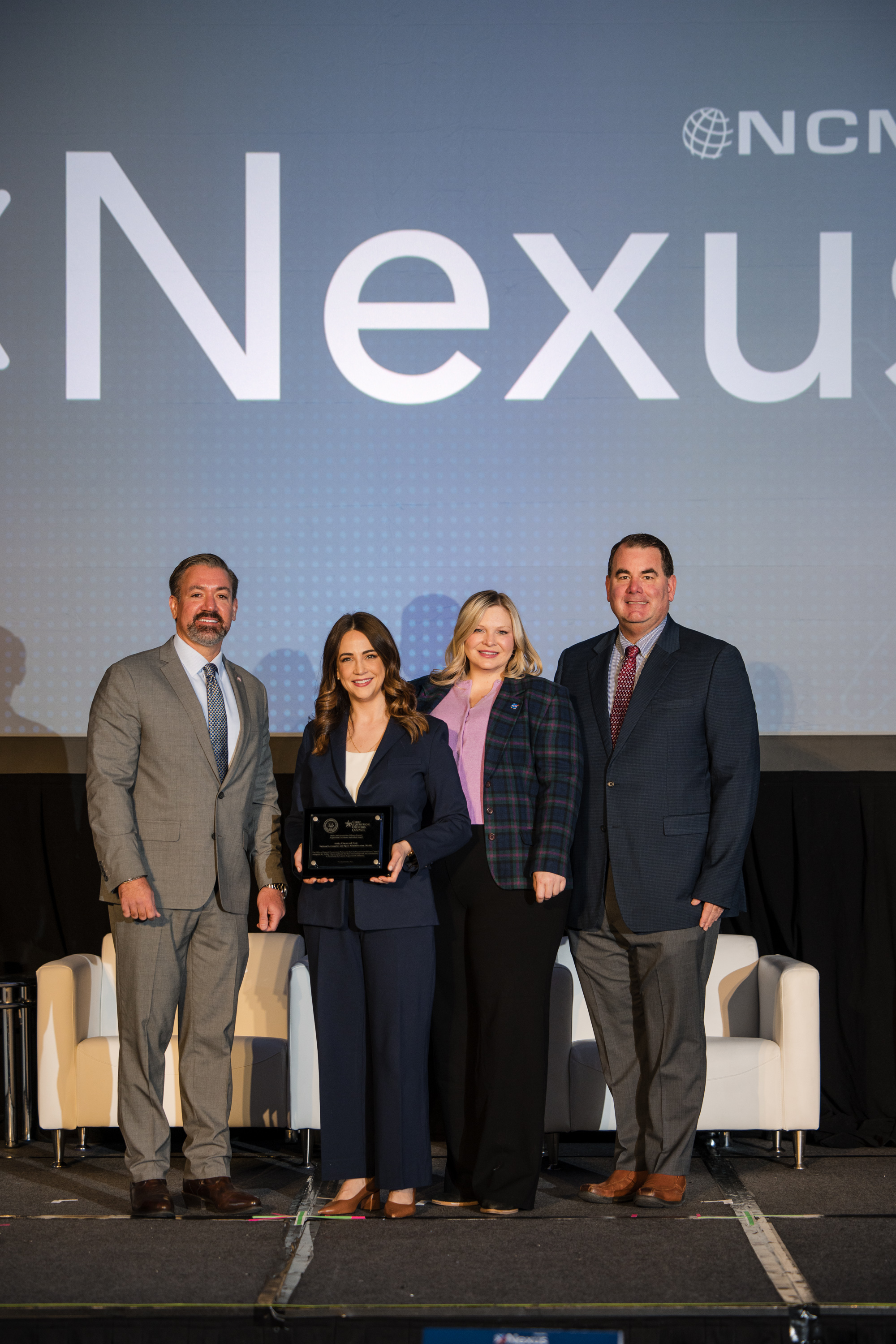 Dr. Kevin Rhodes, Administrator of the Office of Federal Procurement Policy (left), presents Ashley Chaves, Audrey Montgomery, and Michael Boggs with the Acquisition Excellence Team Award.